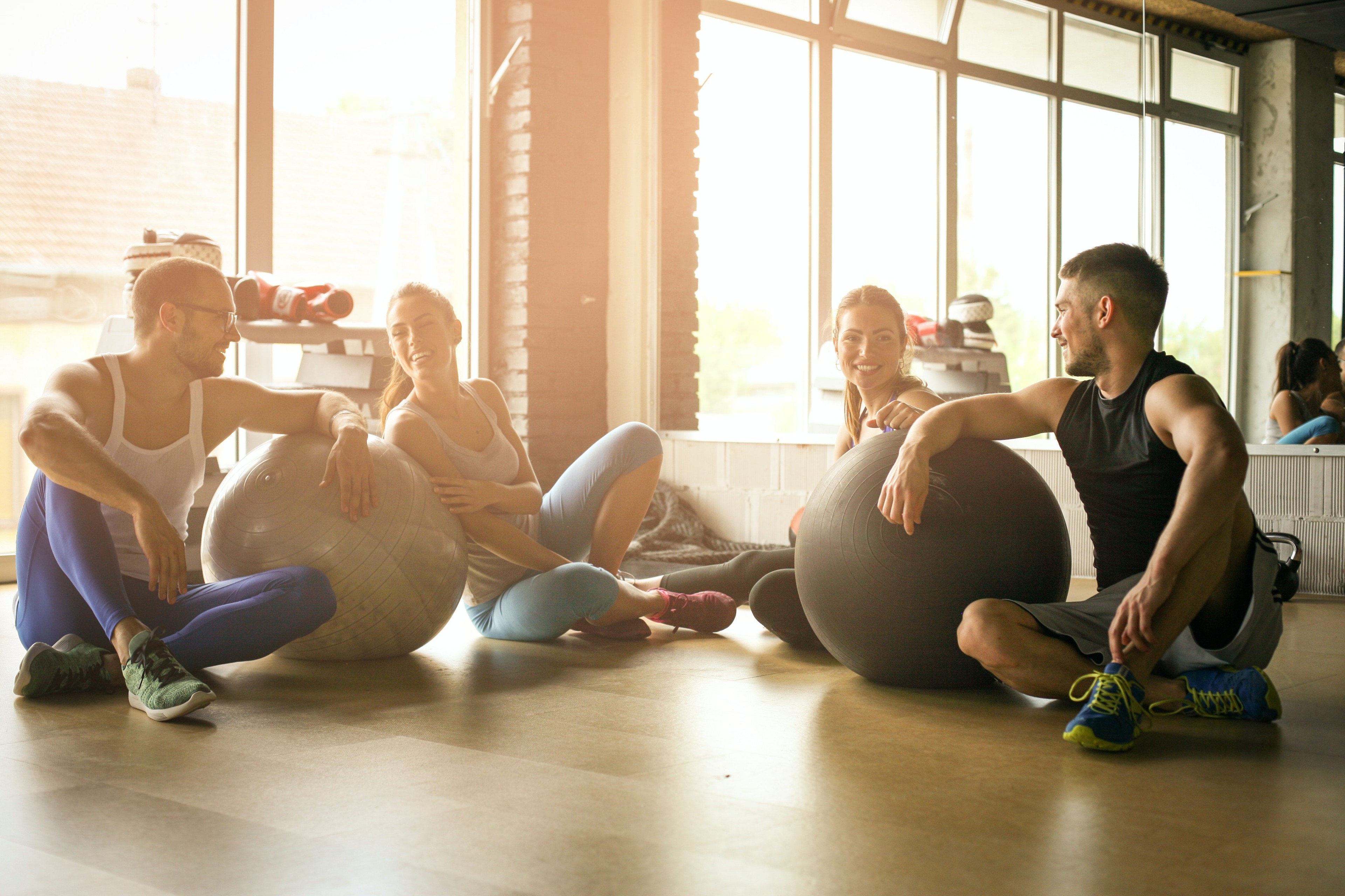 Mehrere Personen sitzen mit Fitnessbällen im Fitnessstudio.