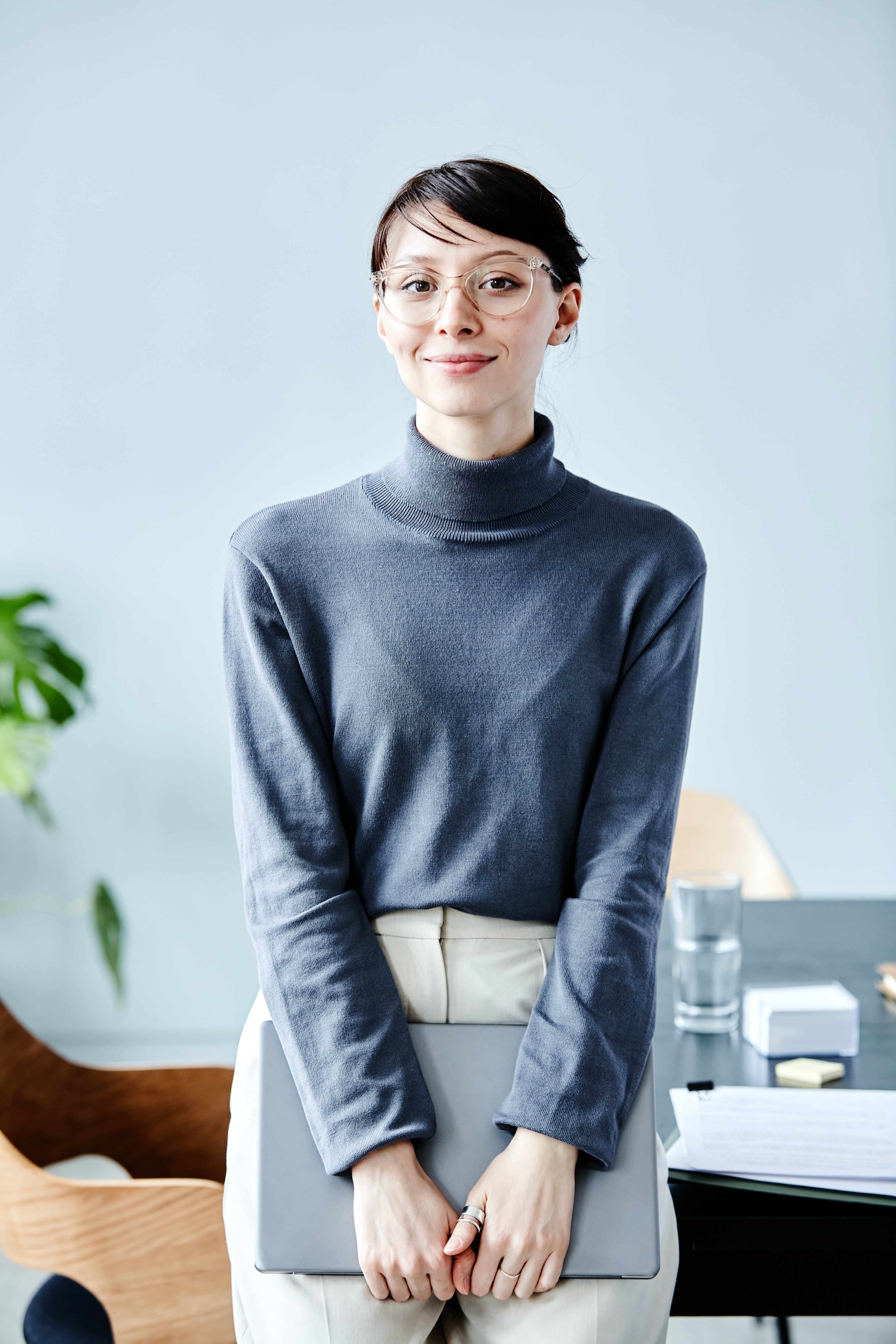 Frau angelehnt am Tisch mit zugeklapptem Laptop im Office.