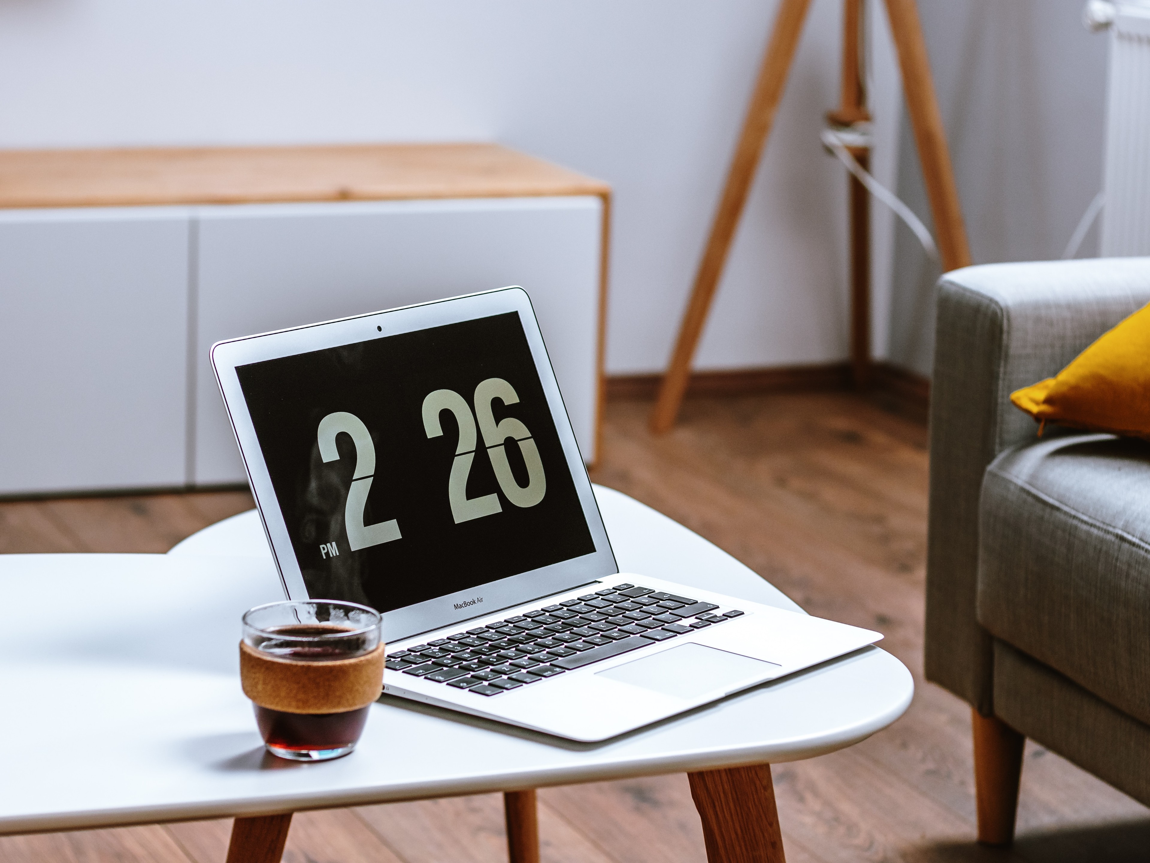 Laptop mit dem Hintergrundbild einer digitalen Uhr auf dem Tisch eines Wohnzimmers platziert.