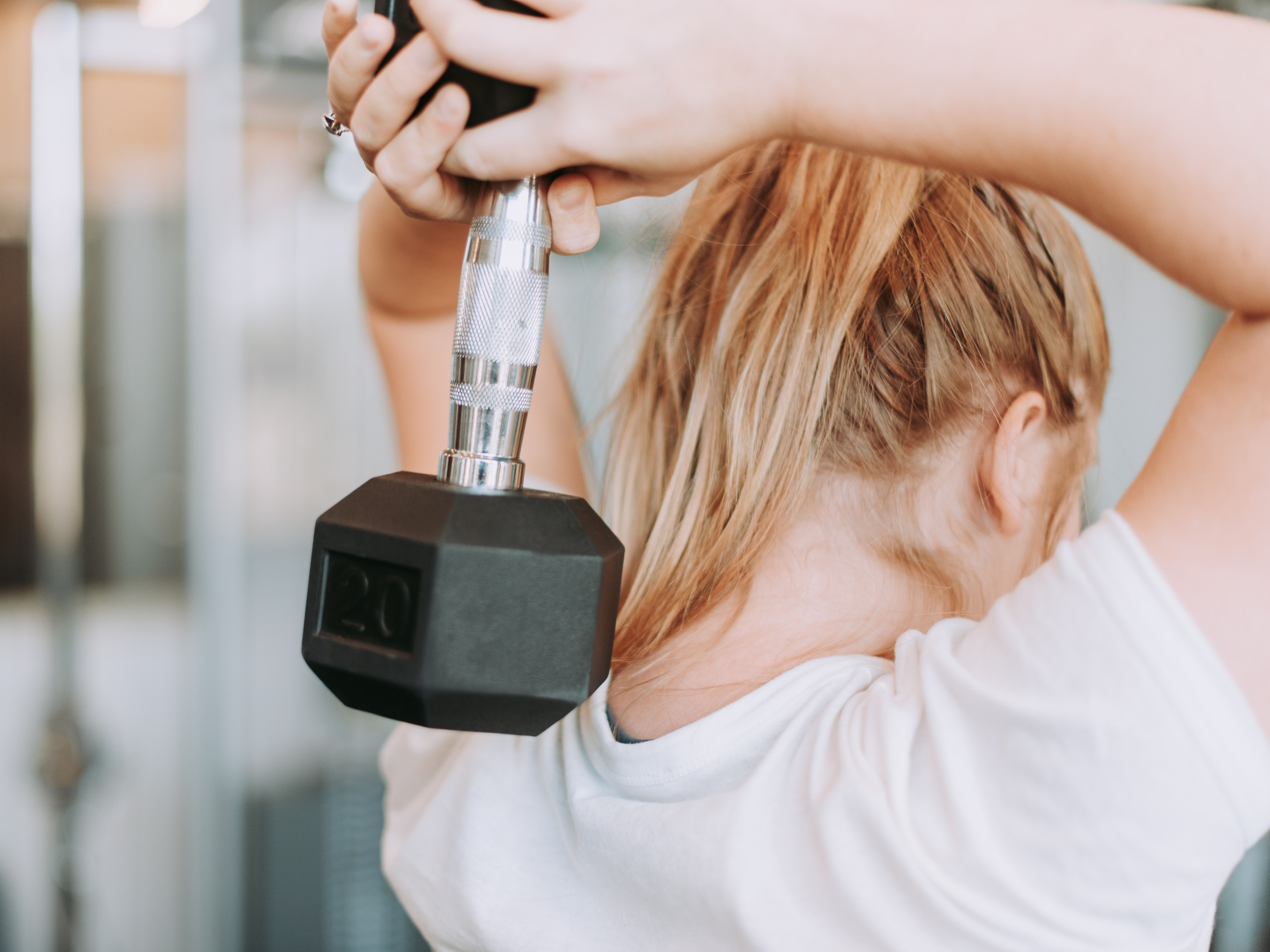 Frau im Fitnessstudio beim Hanteltraining.