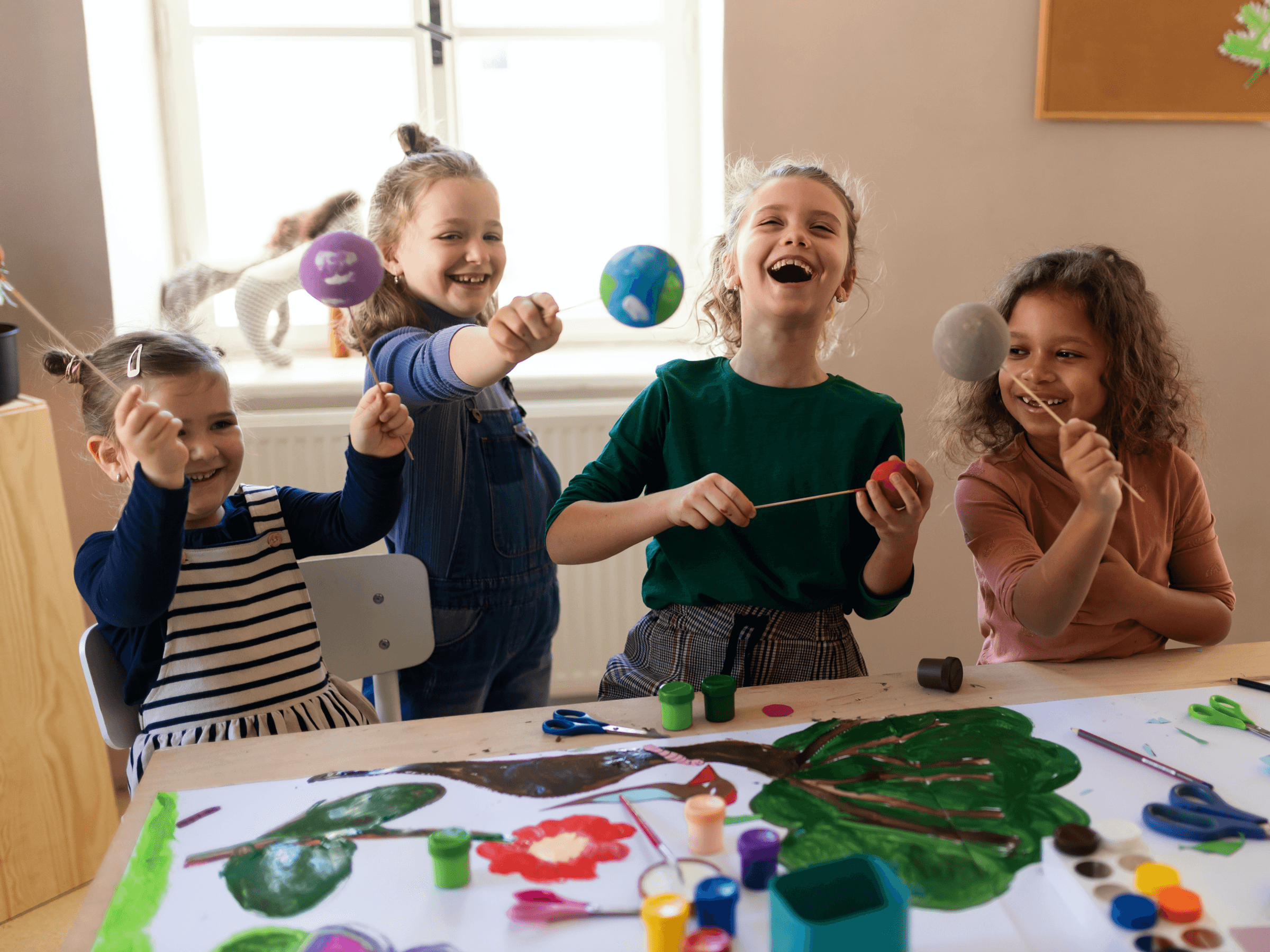 Mehrere Kinder, die lachend ein Naturbild mit Tuschefarben malen.