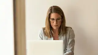 Headerbild zeigt Frau am Laptop mit Kopfhörern im Ohr, die die Prozessautomatisierung mithilfe von askDANTE vorantreibt.