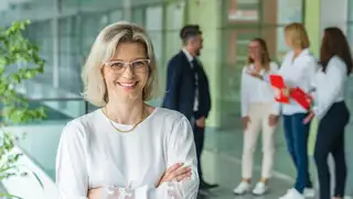 Headerbild zeigt eine Personalerin im Vordergrund und ihre Mitarbeiter im Hintergrund, für die sie eine Personalbedarfsplanung mithilfe von askDANTE erstellt hat.