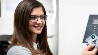 Headergrafik zeigt eine Mitarbeiterin, die sich mit einer Stempelkarte von askDANTE an einem Zeiterfassungsterminal einstempelt.