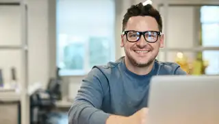 Headerbild zeigt einen zufriedenen Mitarbeiter am Laptop, dem HR mithilfe von askDANTE Überstunden auszahlen konnte.