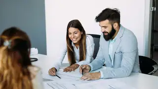 Headerbild zeigt zwei Mitarbeiter im Office, die am Schreibtisch in Vertrauensarbeitszeit arbeiten.