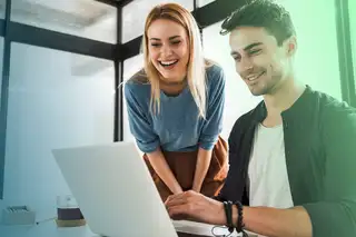 Headerbild zeigt zwei Mitarbeiter, die sich am Laptop mit der Kernarbeitszeit in askDANTE befassen.