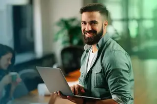 Headerbild zeigt einen Mitarbeiter mit Laptop, der auf einem Schreibtisch sitzt und mit askDANTE arbeitet.