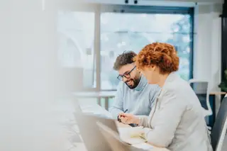 zwei hr mitarbeiter im buero arbeiten am schreibtisch und sind im gespraech