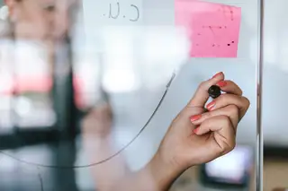 grafik zeigt hand die an glaswand schreibt mit postits